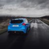 The image shows a blue Ford Focus RS MK3 dirivinf down a country road during stormy weather.